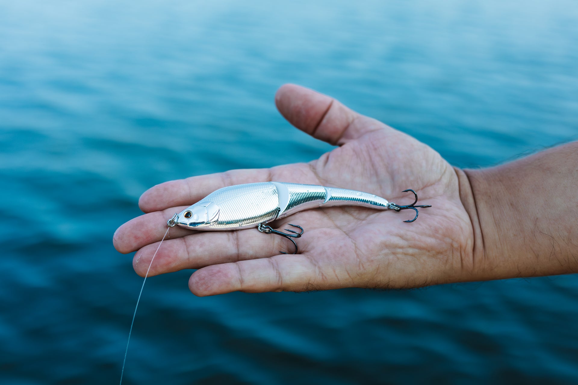 An angler poses his hand with a Magic Swimmer® Freshwater bait about the water on Lake Murray