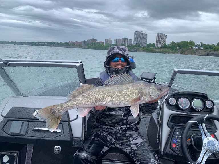 Man smiling holding large fish on a boat