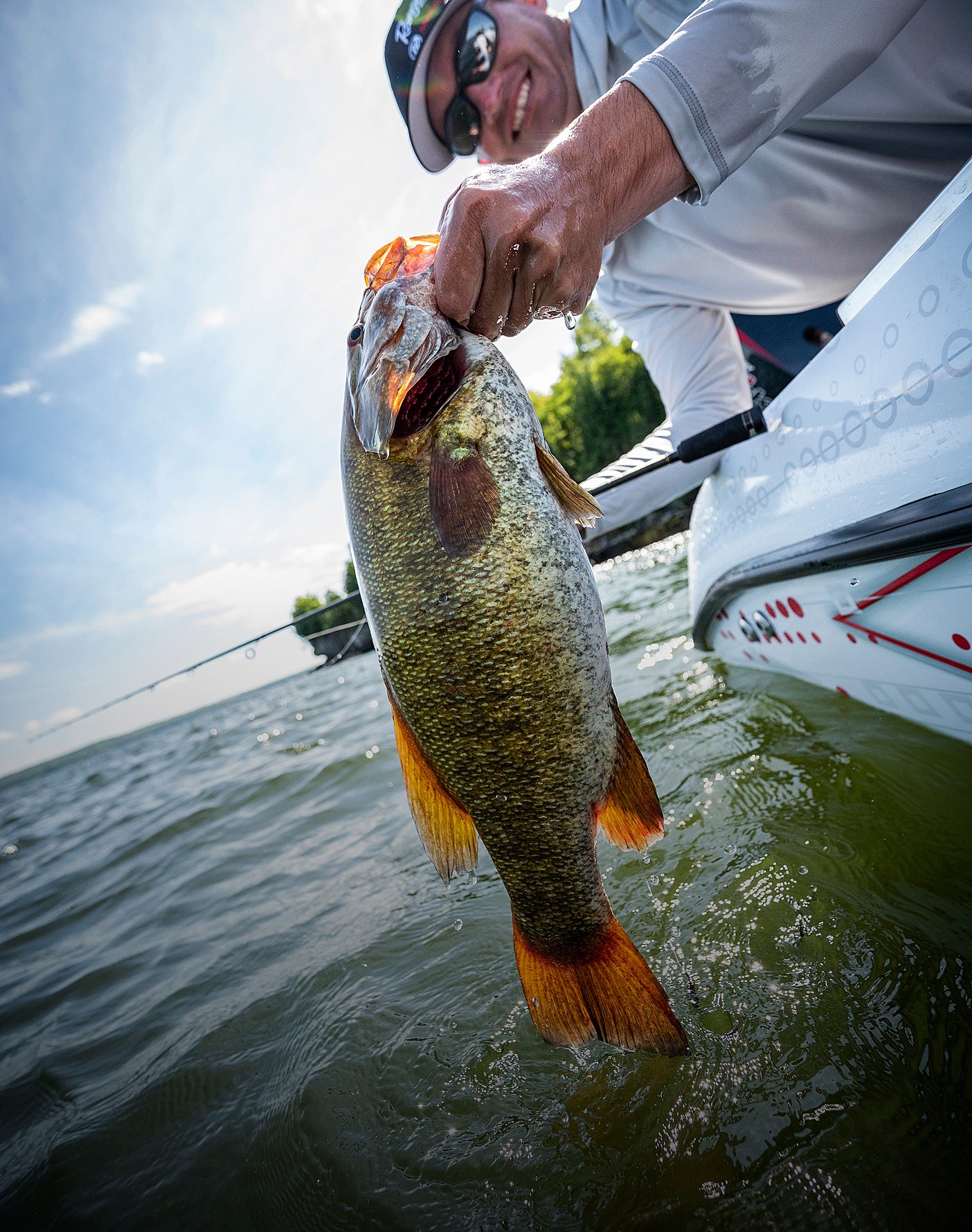 Man holding a large fish caught from a boat on a lake