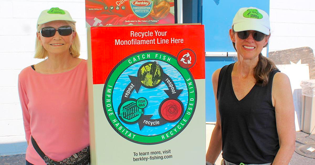 2 women smiling in front of sign for recyclable line