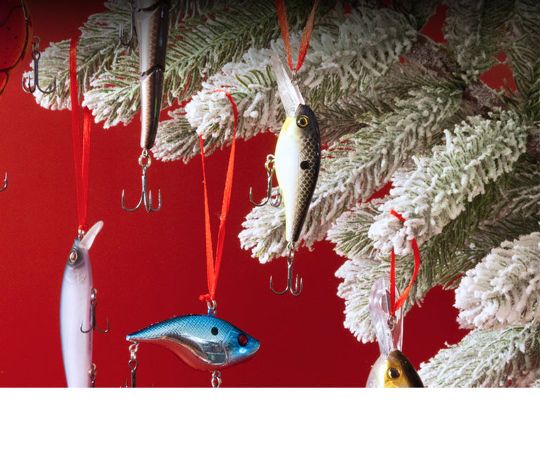 Decorative fishing lures hanging from a Christmas tree against a red background