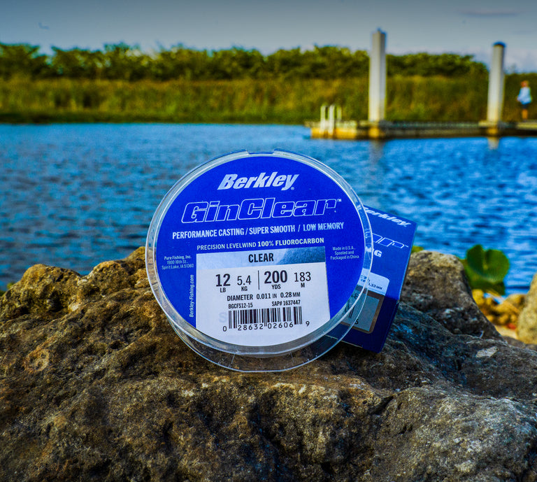 Berkley fishing line spool on a rock with a lake and dock in the background