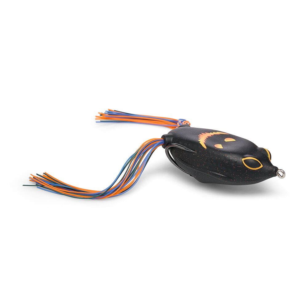 A black fishing lure with a jack-o-lantern face graphic in orange and yellow, featuring a multi-colored skirt with orange, blue, and black strands, shown on a white background.