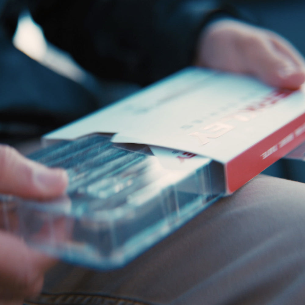 Person holding a clear plastic container with a red and white box inside