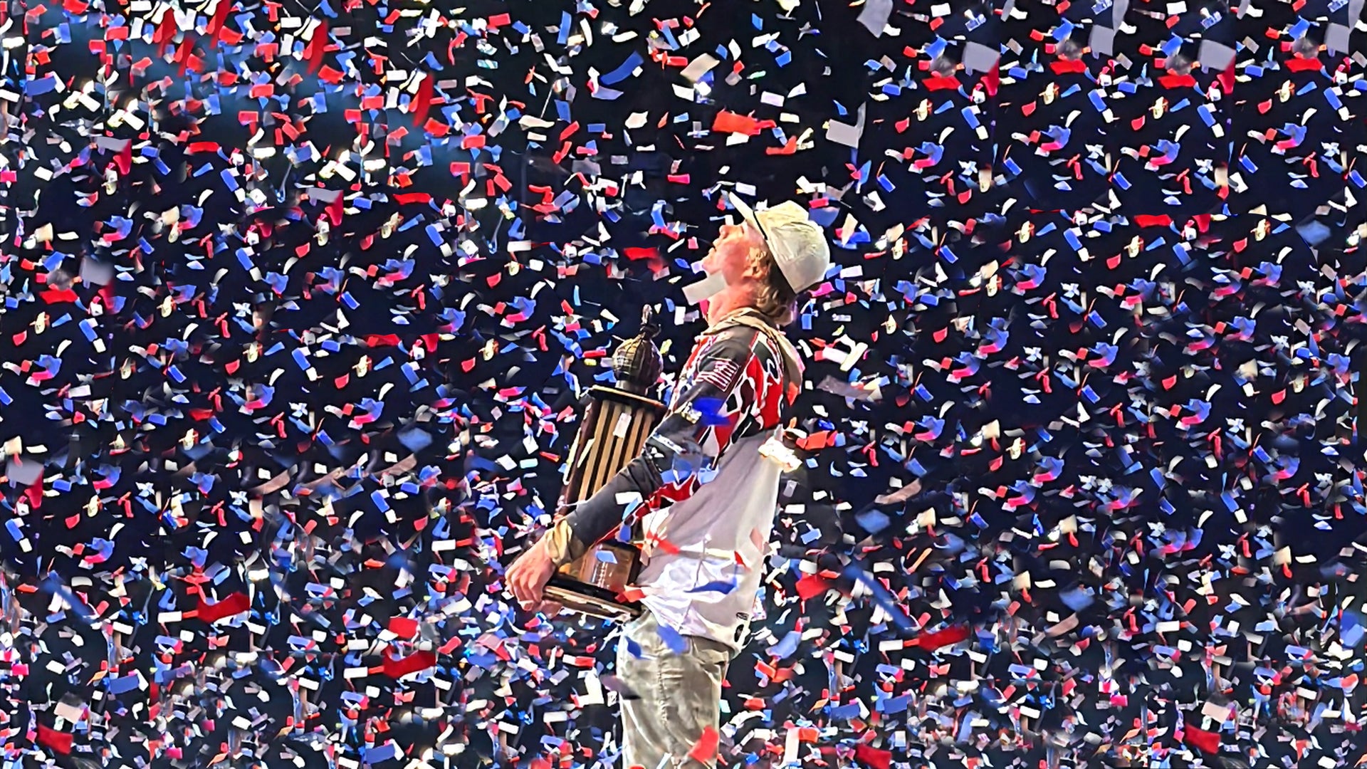 Person holding a trophy amidst a shower of confetti in a celebratory setting